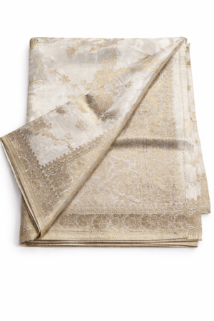 Luxurious ivory Banarasi silk saree adorned with intricate gold zari weaving, a regal border, and a striking contrast red blouse piece for timeless festive elegance.