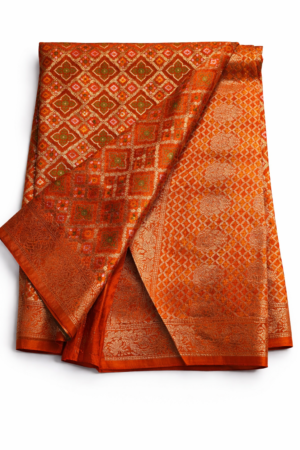 A luxurious burnt orange Bandhani saree featuring intricate allover zari jaal patterns and rich traditional weaving for a grand festive look.