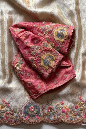 A luxurious peach beige designer organza saree featuring exquisite floral embroidery, scalloped embellished border, and a richly embroidered contrast pink blouse for regal occasion wear.