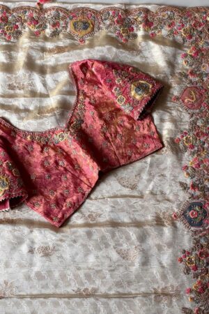 A luxurious peach beige designer organza saree featuring exquisite floral embroidery, scalloped embellished border, and a richly embroidered contrast pink blouse for regal occasion wear.