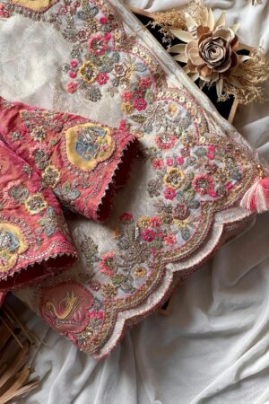 A luxurious peach beige designer organza saree featuring exquisite floral embroidery, scalloped embellished border, and a richly embroidered contrast pink blouse for regal occasion wear.