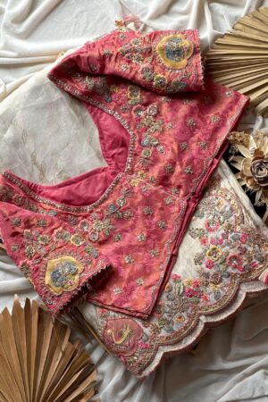 A luxurious peach beige designer organza saree featuring exquisite floral embroidery, scalloped embellished border, and a richly embroidered contrast pink blouse for regal occasion wear.