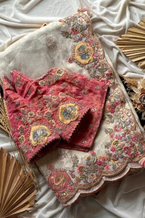 A luxurious peach beige designer organza saree featuring exquisite floral embroidery, scalloped embellished border, and a richly embroidered contrast pink blouse for regal occasion wear.
