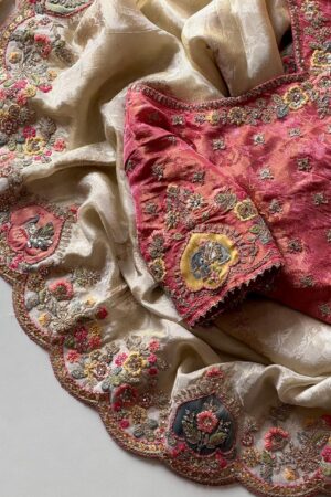 A luxurious peach beige designer organza saree featuring exquisite floral embroidery, scalloped embellished border, and a richly embroidered contrast pink blouse for regal occasion wear.