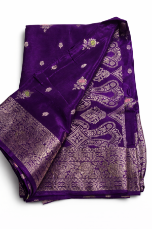 A regal royal purple Banarasi soft silk saree featuring delicate woven butis, an opulent floral zari border, and an intricately woven paisley pallu for timeless festive elegance.