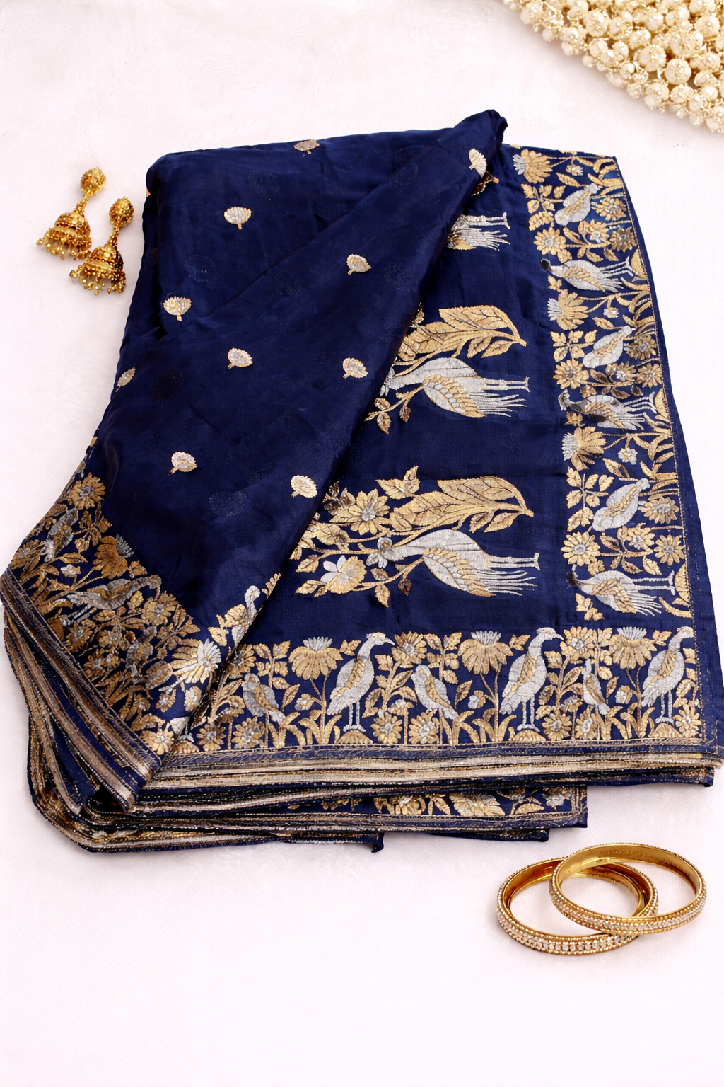 Elegant navy blue Banarasi soft silk saree featuring delicate silver buti motifs and a stunning floral bird woven border for a rich designer festive look.
