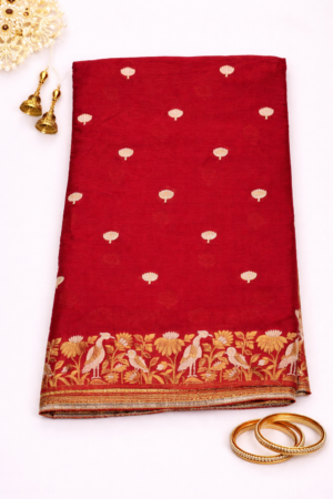 Stunning red Chinon silk saree adorned with elegant gold buti motifs and a richly woven traditional zari border for timeless festive charm.
