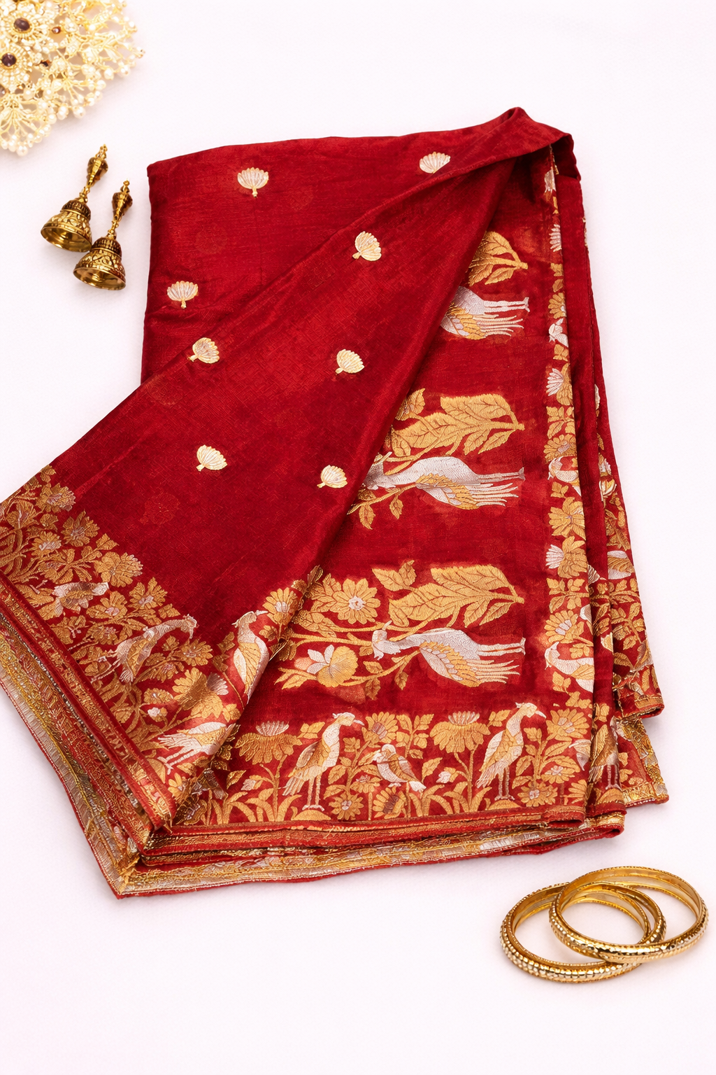 Stunning red Chinon silk saree adorned with elegant gold buti motifs and a richly woven traditional zari border for timeless festive charm.