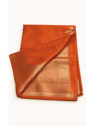 Striking burnt orange raw mango silk saree adorned with elegant floral silver zari motifs and a refined woven border for timeless festive charm.