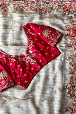 A breathtaking off white designer organza saree paired with a vibrant rani pink embroidered blouse and richly detailed multicolor border work, crafted for luxurious festive and wedding celebrations.