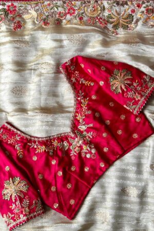 A breathtaking off white designer organza saree paired with a vibrant rani pink embroidered blouse and richly detailed multicolor border work, crafted for luxurious festive and wedding celebrations.