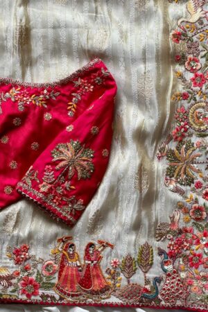 A breathtaking off white designer organza saree paired with a vibrant rani pink embroidered blouse and richly detailed multicolor border work, crafted for luxurious festive and wedding celebrations.