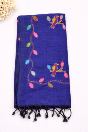 Elegant navy blue pure linen saree featuring colorful bird and leaf embroidery with handcrafted charm and soft tassel detailing.