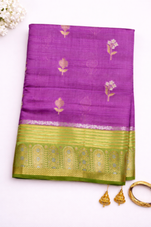 Elegant lavender purple raw mango silk saree featuring delicate floral zari motifs and a graceful olive green contrast woven border for a refined festive look.