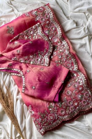 A dreamy blush pink organza saree adorned with rich floral sequins embroidery, scalloped embellished borders, and luxurious festive elegance.