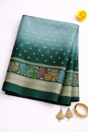 Graceful teal green Tussar Bandhani saree featuring delicate bandhani-inspired butis, vibrant floral border detailing, and elegant silver zari accents.