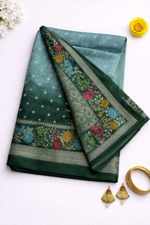Graceful teal green Tussar Bandhani saree featuring delicate bandhani-inspired butis, vibrant floral border detailing, and elegant silver zari accents.